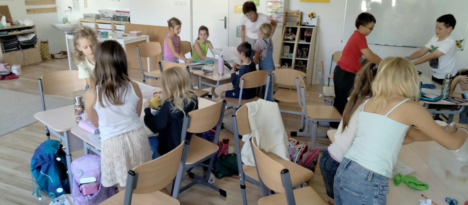 Deti v triede pracujú pri stoloch samostatne aj v skupinkách, medzi nimi sa pohybuje sprievodkyňa